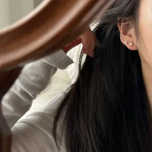 Detailed close-up showing small minimalist sterling silver heart-shaped stud earrings