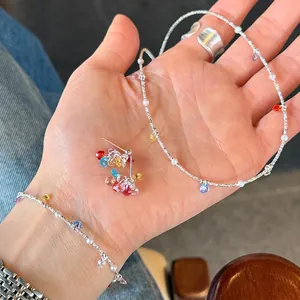 Close-up detail of 925 sterling silver necklace set with colorful zircon charms on palm
