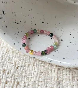 Close-up of handmade tourmaline beaded ring with a gold silver bead on a ceramic dish