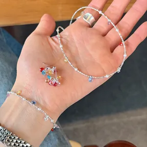 Detail view of 925 sterling silver jewelry set with colorful zircon stones on a person's hand.