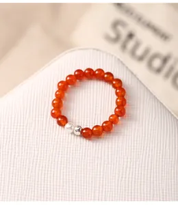 Close-up of orange agate beaded elastic ring featuring a white pearl and silver bead accent