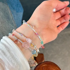 Detailed view of 925 sterling silver bracelets with pink crystals and pearls on wrist.