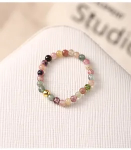 Macro view showing colorful tourmaline gemstone beads and golden silver ball on elastic ring
