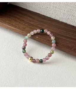 Macro view of a handmade elastic ring featuring colorful tourmaline beads and a single gold bead