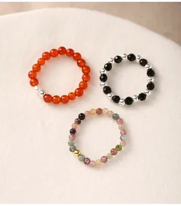 Close-up macro shot of three stretch beaded rings featuring natural agate and tourmaline