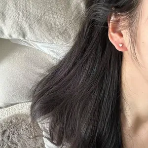 Close-up of minimalist sterling silver heart stud earring worn on earlobe