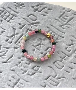 Detail view of colorful tourmaline beaded ring with a gold silver bead on stone.
