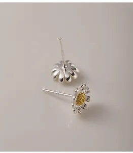 Primer plano de elegantes pendientes de margarita de plata de ley 925 con sello S925