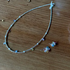 Close-up view of 925 silver necklace and colorful zircon earrings on wooden background.