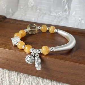 Zilveren armband met honingwas kralen en bedeltjes van een pinda en een belletje