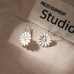 Elegantes pendientes de margarita en plata de ley 925 sobre tela texturizada beige