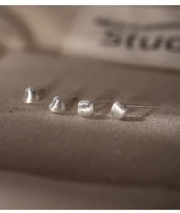 Macro detail of frosted 990 sterling silver heart and square stud earrings