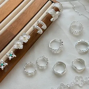 Vista detallada de joyas de plata S925 con patrones de encaje y pendientes de flores