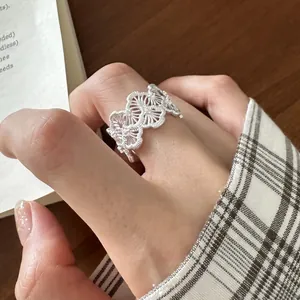 Close-up of 925 sterling silver hollow lace ring with delicate stone inlay on finger.