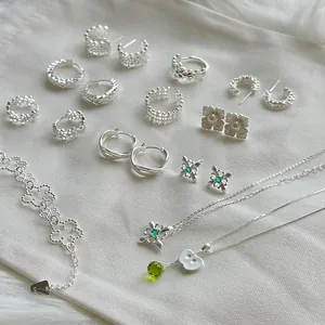 Colección detallada de joyas de plata s925 con patrones de encaje y piedras verdes.