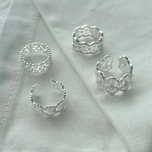 High-definition close-up of four intricate silver lace filigree rings on white textured fabric