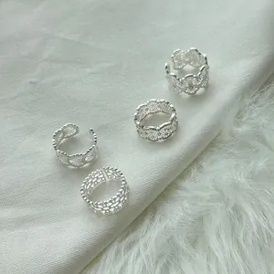 Detail of four 925 sterling silver lace rings on soft textured fabric and faux fur.