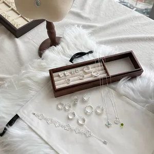 Primer plano de pulsera de encaje de plata S925 y conjunto de joyas en bandeja de madera.