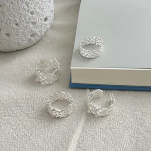 Detail of 925 silver lace filigree rings set with hollow patterns on textured fabric.