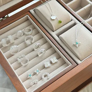 Primer plano de anillos y collares de plata s925 en un joyero de madera elegante