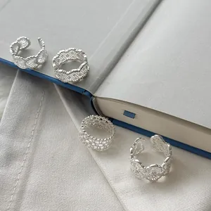 Close-up of four intricate 925 sterling silver lace pattern hollow rings on a book