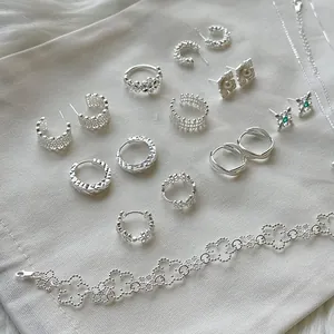 Vista detallada de varios pendientes, anillos y pulseras de plata S925 sobre tela