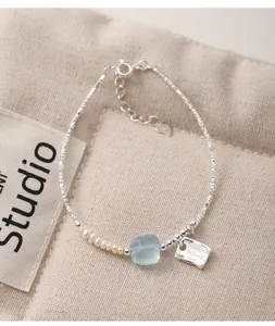 Detail of 925 sterling silver bracelet with pearls and a blue aquamarine stone.