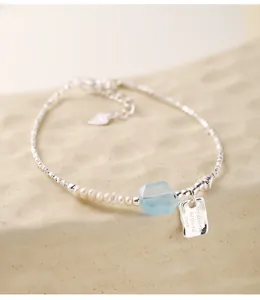 Detail view of sterling silver bracelet with pearls, aquamarine, and engraved tag