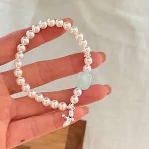 Vista detallada de pulsera de perlas con cristal azul claro y ave de plata