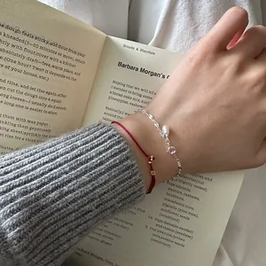 Close-up of 925 sterling silver pearl bracelet layered with red cord flower charm