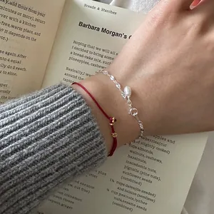 Close-up of 925 silver pearl bracelet and red cord coin bracelet layered on a wrist.