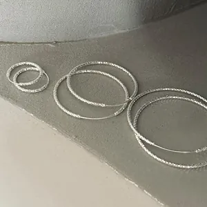 Detalle de pendientes de aro de plata de ley con una textura de estrellas brillante