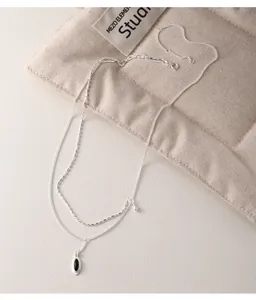 Detail of 925 sterling silver double-layered necklace with oval black agate pendant