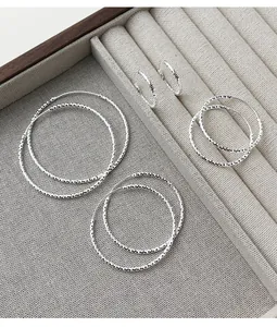 Vista detallada de pendientes de aro de plata brillante en varios tamaños en un joyero