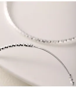Detalle del sello S925 en pendientes de aro de plata de ley con textura tallada