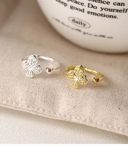 Two elegant 925 silver and gold plum blossom open rings with red zircon on beige fabric