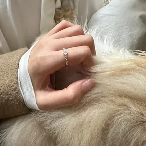 Close-up detail of 925 sterling silver four-leaf clover chain ring worn on hand over soft fur