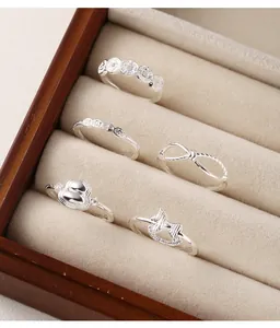 Close-up view of five 999 sterling silver rings set in a cream velvet jewelry box