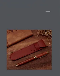 Dettaglio macro di un astuccio per penne in pelle rossa e penna a sfera in legno pregiato