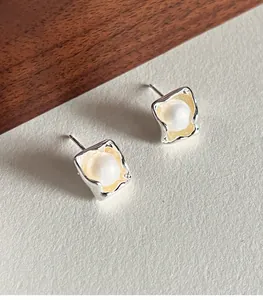 Detailed macro view of irregular 925 silver square stud earrings with pearls