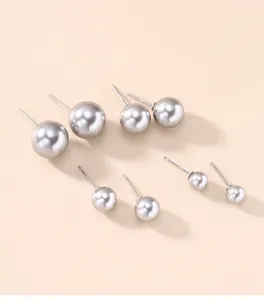 Detailed macro view showing four different sizes of elegant gray round pearl stud earrings