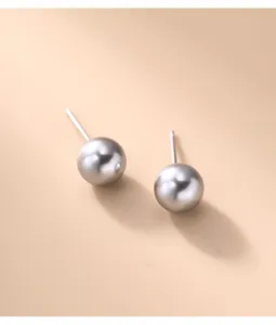 Macro detail of elegant round grey pearl stud earrings with a lustrous finish.