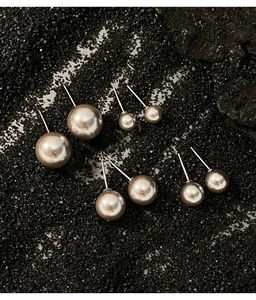 Close-up of elegant round grey pearl stud earrings in various sizes on dark background