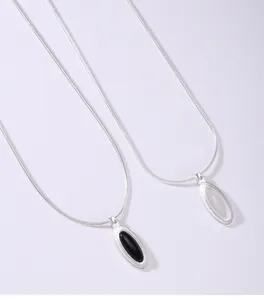Close-up of silver snake chain necklaces with oval black onyx and white chalcedony pendants.