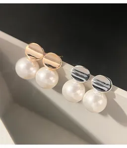 Detail shot of irregular metal disc and pearl stud earrings in gold and silver.