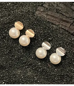 Macro view of sterling silver and white pearl stud earrings on textured black sand