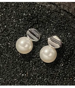 Macro shot of minimalist irregular silver plate and white pearl stud earrings