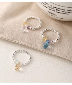 Macro detail of 925 silver beaded rings featuring faceted colorful crystal teardrops