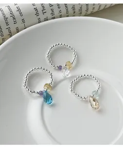 Detailed macro view of three elastic beaded silver rings with colorful teardrop crystal charms