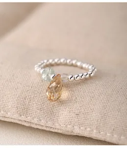 Detail view of S925 silver beaded elastic ring with champagne crystal teardrop